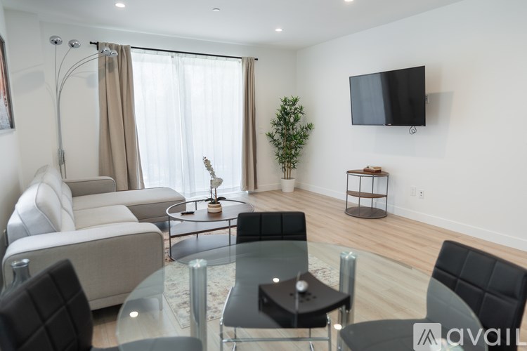 A modern living room with a glass table and black chairs.