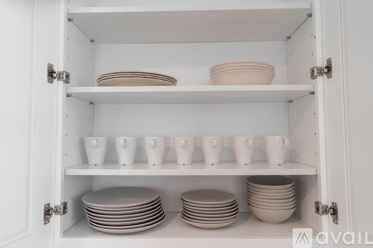 A white cabinet with plates and bowls on the shelves.