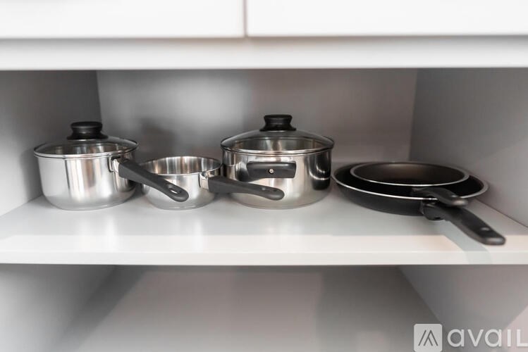 A white shelf with pots and pans on it.