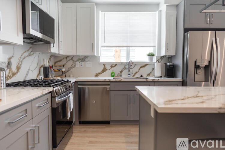 A kitchen with a marble countertop and stainless steel appliances.