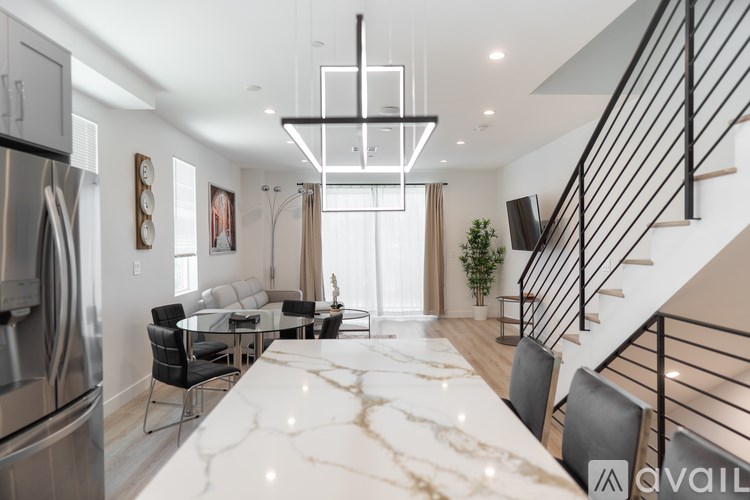A modern kitchen with a marble countertop and a stainless steel refrigerator.
