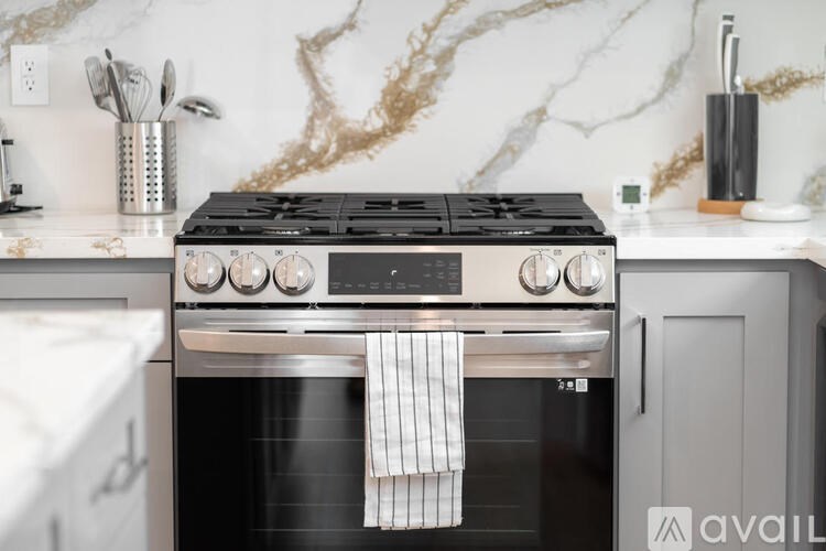 A modern kitchen with a black stove top oven and a marble backsplash.