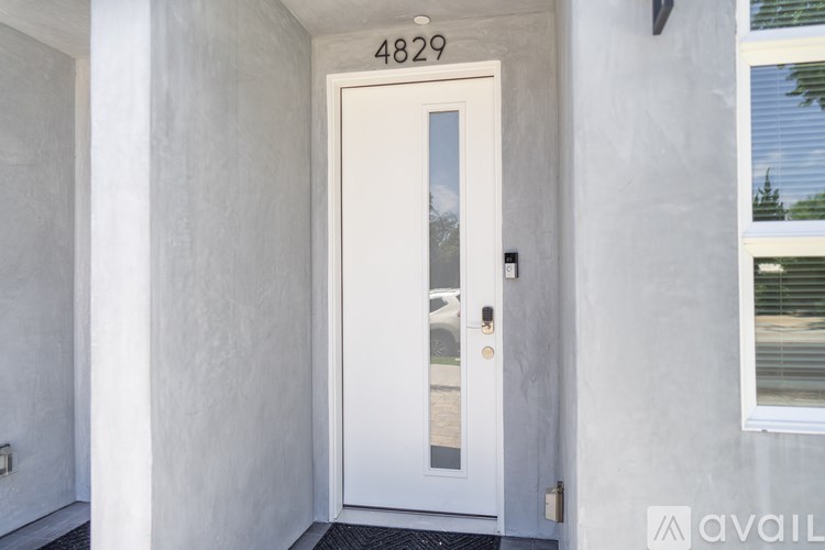 A white door with a glass window and a black handle is on the front of a building.
