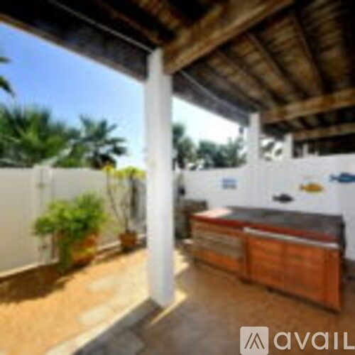 A patio with a white fence and a wooden roof.