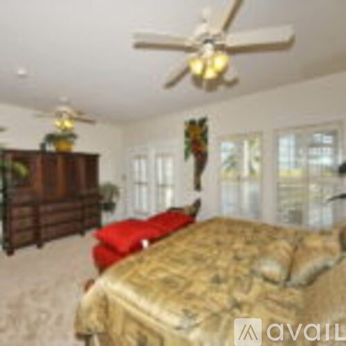 A bedroom with a bed, a dresser, and a ceiling fan.