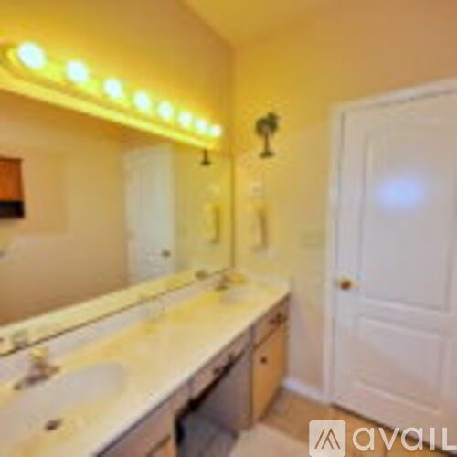 A bathroom with a vanity and a mirror with lights above it.