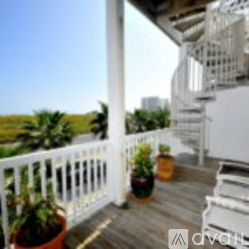 A balcony with a white railing and potted plants.