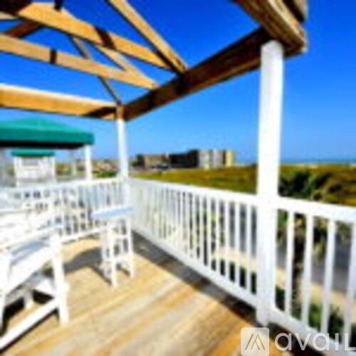 A wooden deck with white railings and a green awning.