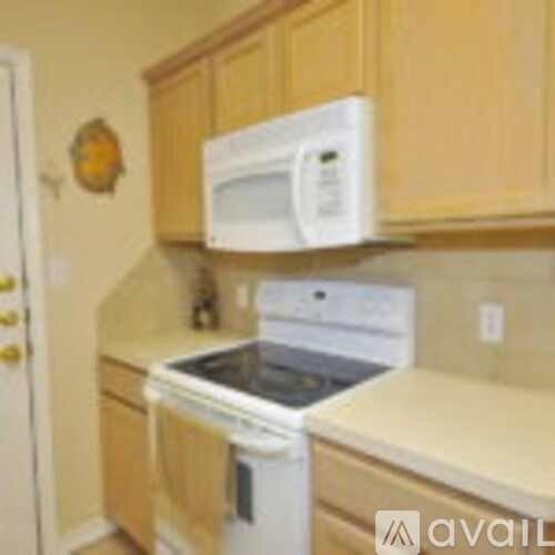 A white microwave oven is mounted above a white dishwasher in a kitchen.