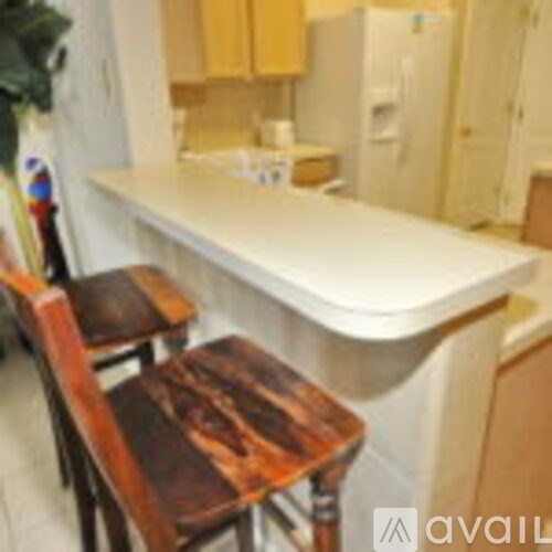 A kitchen with a white counter and wooden chairs.