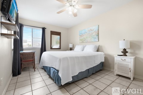 A bedroom with a bed, a ceiling fan, and a painting on the wall.