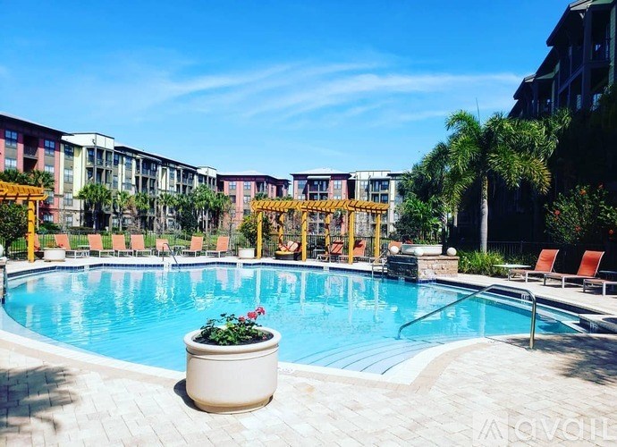 A pool area with a sun lounger and a building in the background.