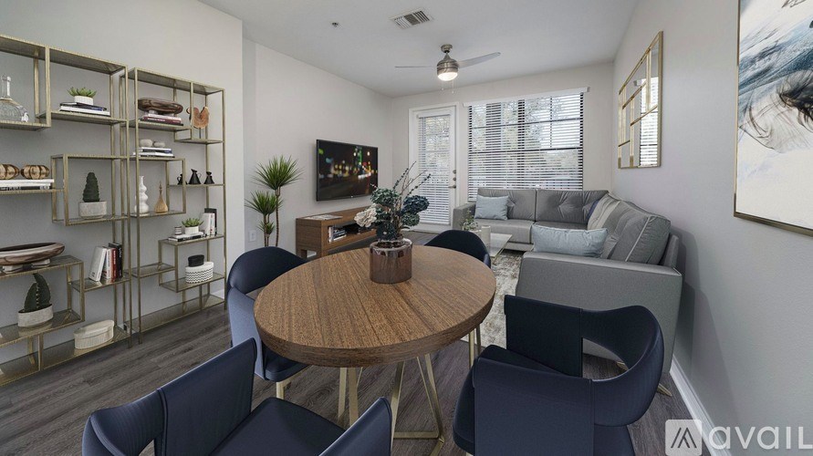 A modern living room with a round wooden table surrounded by blue chairs.
