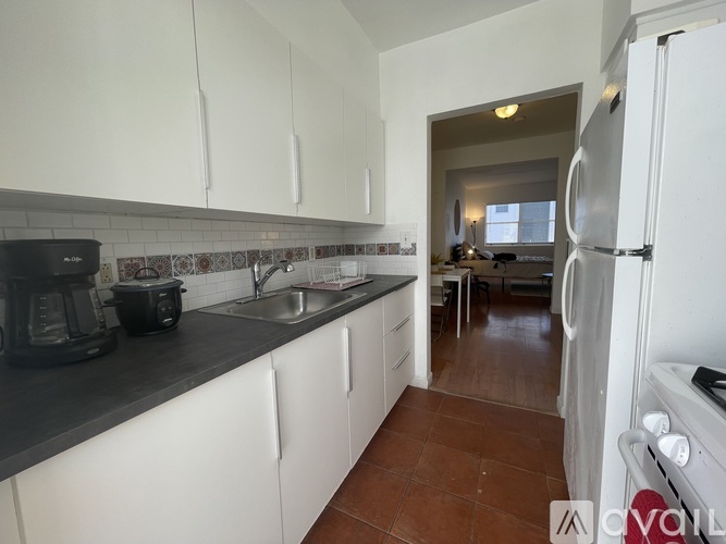 A kitchen with white cabinets and a black coffee maker.