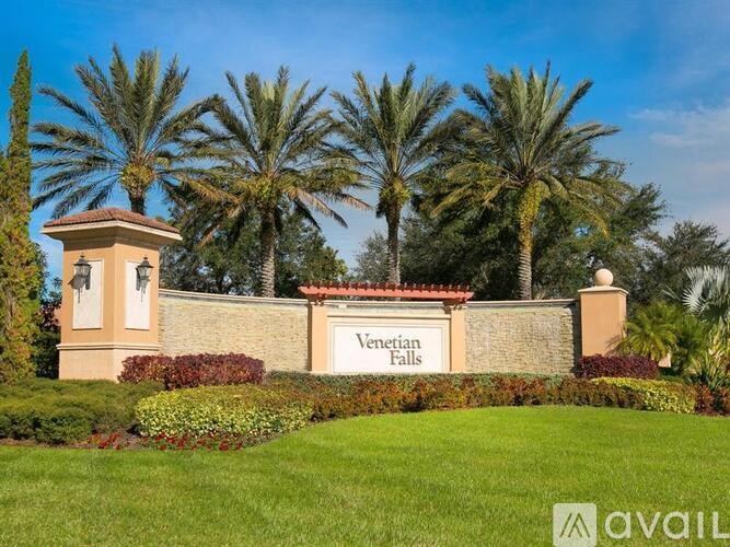 A sign that says Venetian Falls in front of a building and palm trees.