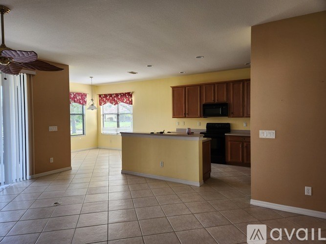 A spacious living room with a kitchen area in the background.