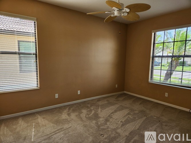 A room with a ceiling fan and two windows.