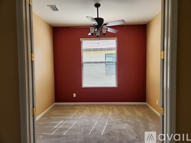 A room with a ceiling fan and a window with blinds.