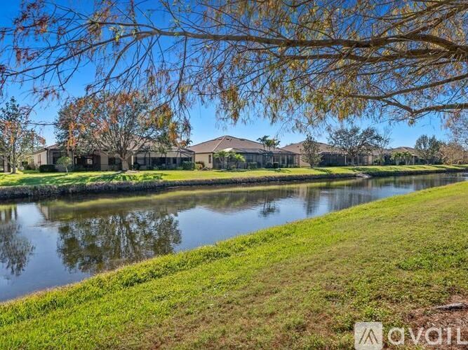 A serene landscape with a pond, houses, and trees.