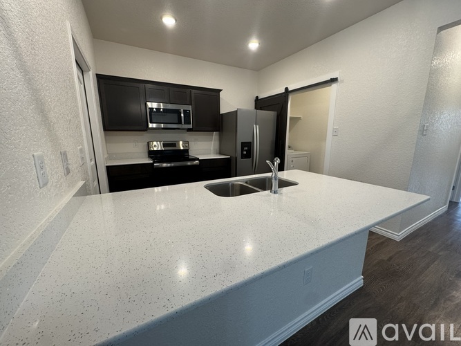 A kitchen with a white countertop and a black fridge.