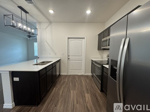 A modern kitchen with a refrigerator on the right and a sink in the middle.