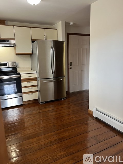 A kitchen with a stainless steel refrigerator and wooden floors.