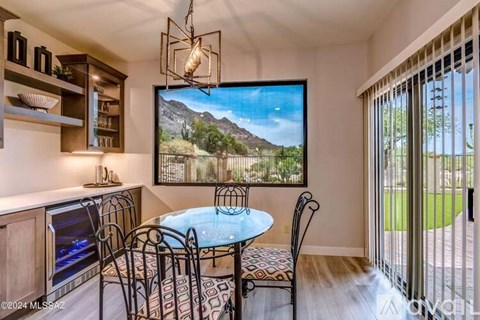 A dining room with a table set for four and a large painting of a mountain scene on the wall.