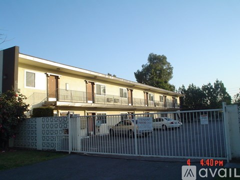 A white fence surrounds a building with a sign that reads "Available".