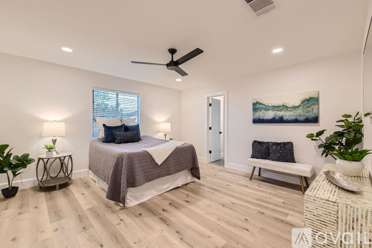 A bedroom with a bed, a bench, and a painting on the wall.