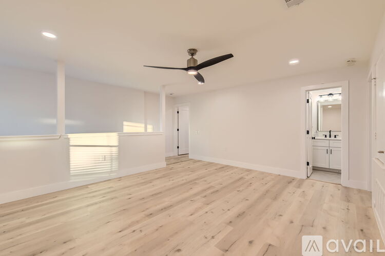 A spacious room with wooden flooring and a ceiling fan.