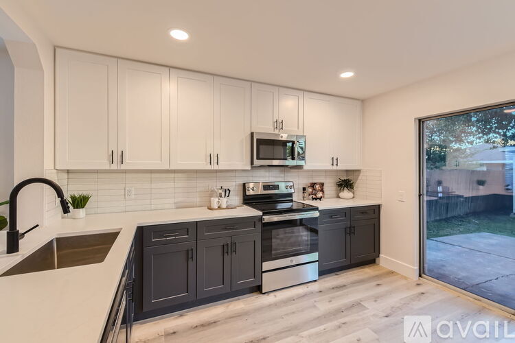 A kitchen with white cabinets and a black countertop.