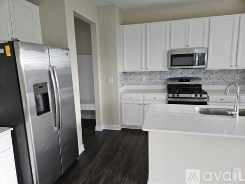 A kitchen with a stainless steel refrigerator and white cabinets.
