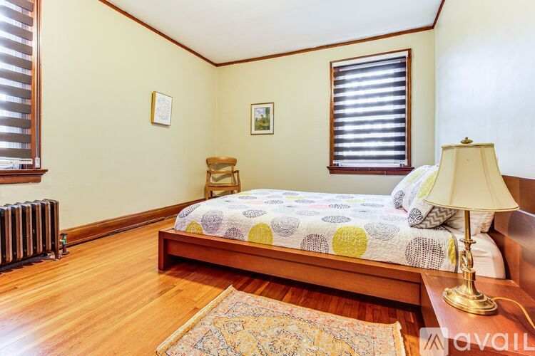 A bedroom with a bed, a chair, a lamp, and a window with blinds.