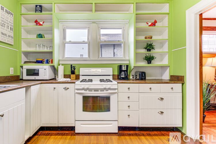 A kitchen with white cabinets and a green wall.