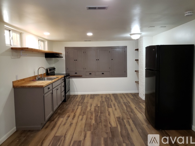 A kitchen with wooden floors and a black refrigerator.
