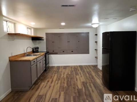 A kitchen with wooden floors and a black refrigerator.
