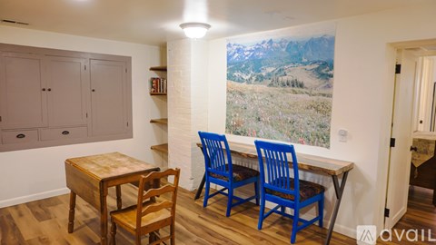A room with wooden flooring and two windows.