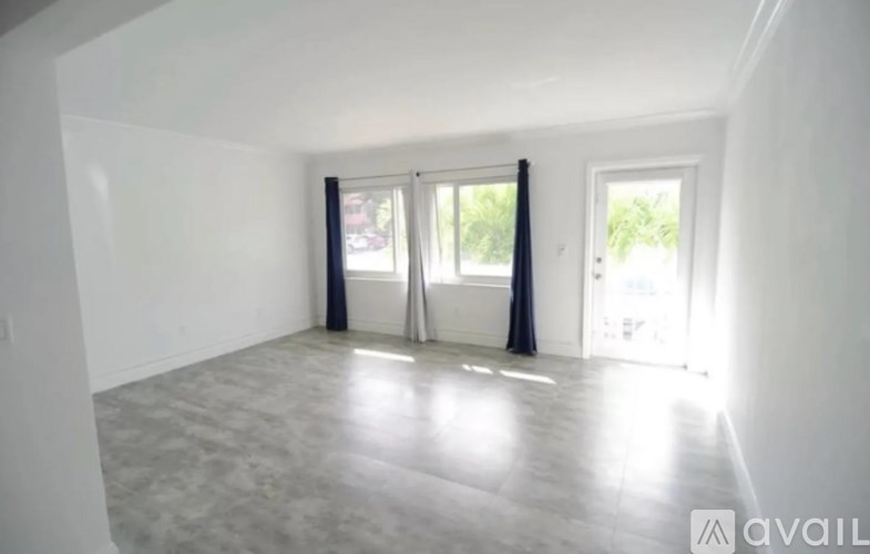 A spacious room with a large window and a door leading to a balcony.