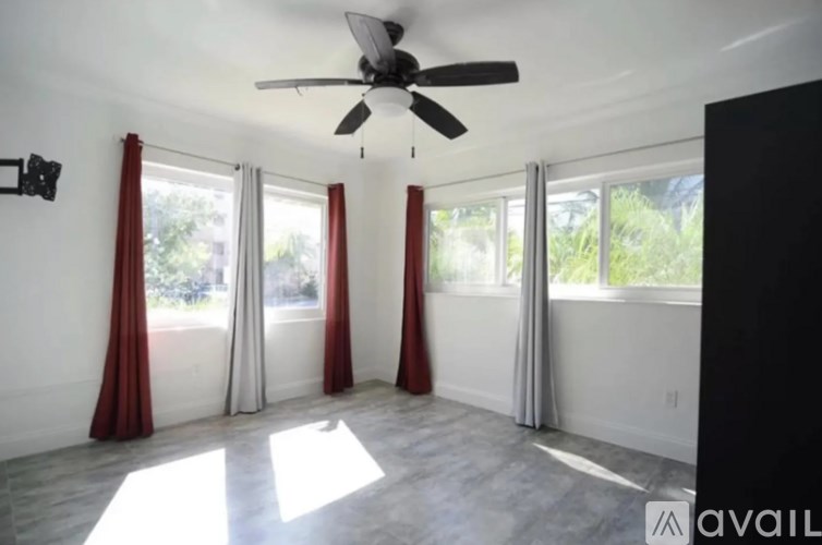 A room with a ceiling fan and sliding glass doors.