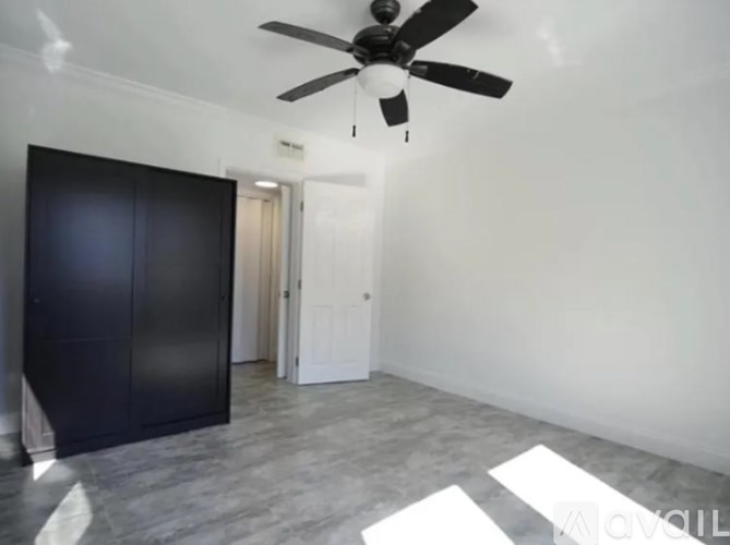 A room with a ceiling fan and a black wardrobe.