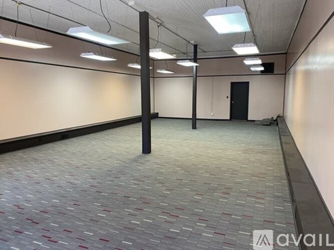 A spacious room with a tiled floor and a row of lights on the ceiling.