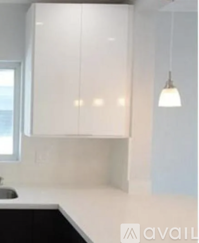 A kitchen with white cabinets and a black counter.