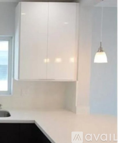 A kitchen with white cabinets and a black counter.