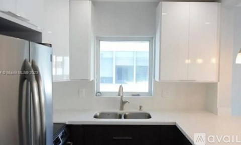 A modern kitchen with a stainless steel refrigerator and a window above the sink.