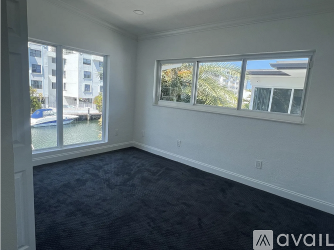 A room with a large window overlooking a pool and buildings.