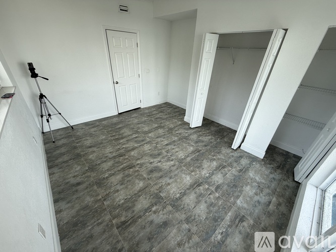 A spacious room with a grey floor and a large mirror on the wall.