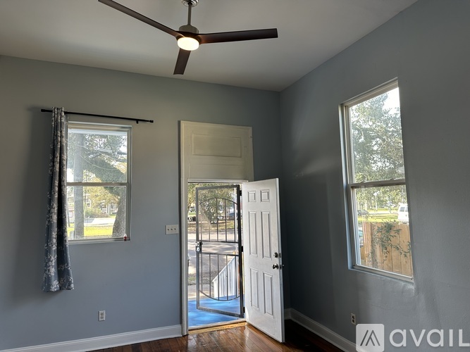 A room with a ceiling fan and two windows.