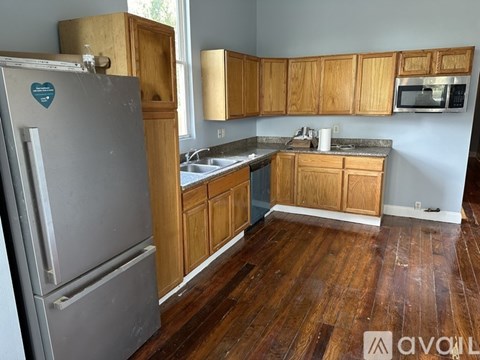 A kitchen with wooden cabinets and a grey fridge.