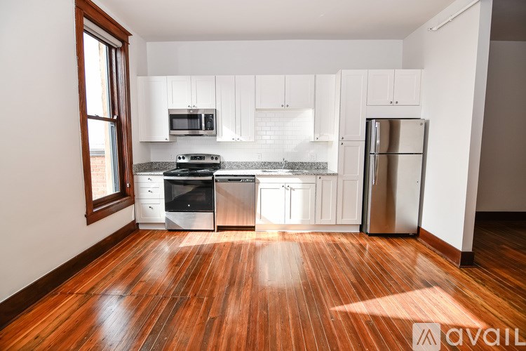 A kitchen with wooden floors and white cabinets.