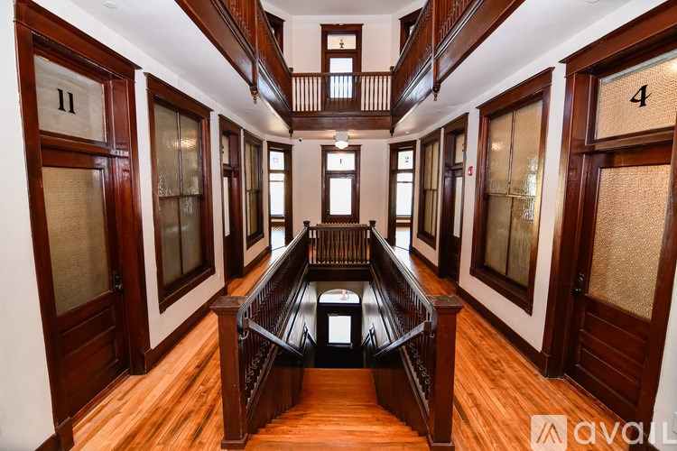 A wooden staircase with a glass railing leads to the upper floor of a house.
